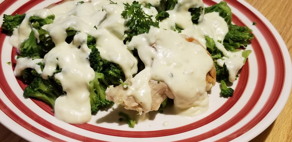 plate of chicken and broccoli covered in alfredo sauce